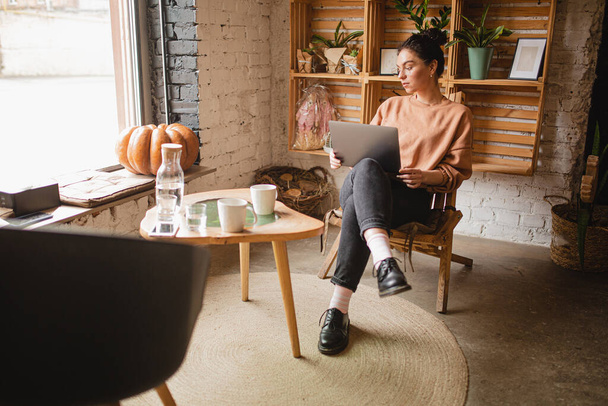 νεαρή γυναίκα κάθεται με φορητό υπολογιστή στο καφέ - Φωτογραφία, εικόνα