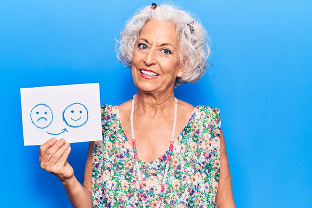 Senior mujer de pelo gris que se siente triste por el papel emotivo feliz que se ve positiva y feliz de pie y sonriente con una sonrisa confiada que muestra dientes.  - Foto, Imagen