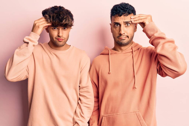 Young gay couple wearing casual clothes worried and stressed about a problem with hand on forehead, nervous and anxious for crisis  - Fotoğraf, Görsel