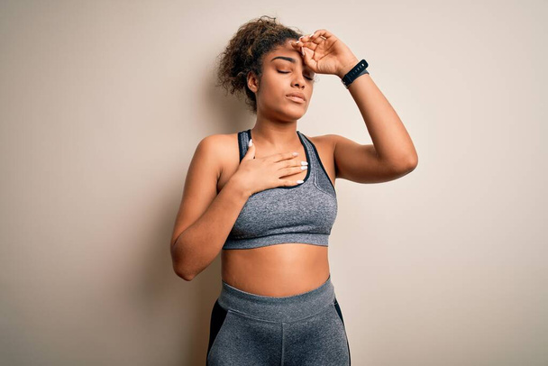 Young african american sportswoman doing sport wearing sportswear over white background Touching forehead for illness and fever, flu and cold, virus sick - Foto, afbeelding