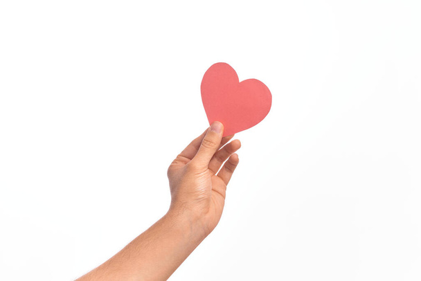 Hand of caucasian young man holding red paper heart shape over isolated white background - Photo, Image