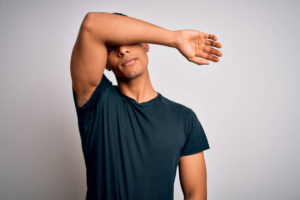 Young handsome african american man wearing casual t-shirt standing over white background covering eyes with arm, looking serious and sad. Sightless, hiding and rejection concept - Фото, изображение