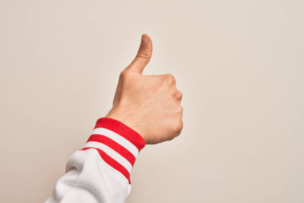 Hand van blanke jongeman met vingers over geïsoleerde witte achtergrond met succesvol goedkeuringsgebaar met duimen omhoog, validatie en positief symbool - Foto, afbeelding