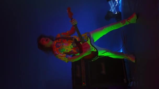 Вертикальное видео танцующего гея, играющего на гитаре на изменяющемся фоне и стробоскопом свете концертного света. Яркие неоновые огни
 - Кадры, видео
