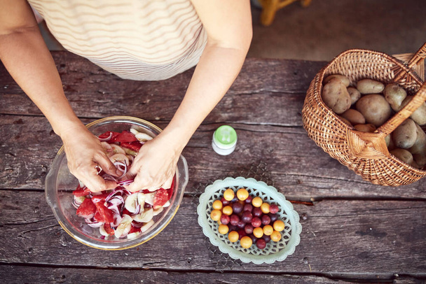 Mujer preparando comida y festín para el almuerzo de verano en el campo casa rústica cocina al aire libre
. - Foto, Imagen