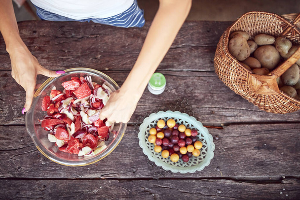 Frau bereitet Essen und Schlemmen für das sommerliche Mittagessen auf dem Land rustikale Hütte Außenküche. - Foto, Bild