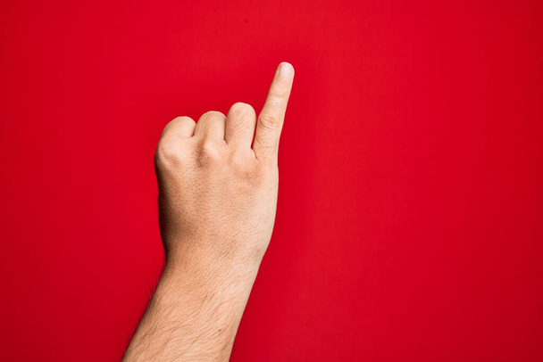 Mano di giovane caucasico che mostra le dita su sfondo rosso isolato mostrando mignolo come impegno promessa mignolo, numero uno - Foto, immagini