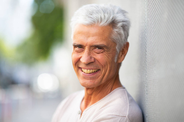 Κοντινό πλαϊνό πορτραίτο όμορφος ηλικιωμένος άντρας χαμογελάει έξω - Φωτογραφία, εικόνα