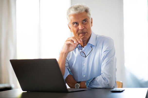 Homem de negócios retrato lateral com óculos sentados na mesa de escritório usando computador portátil
 - Foto, Imagem