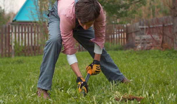 A kertész földet ás az udvaron. Fiatal jóképű férfi lapáttal a mezőn. Emberek, természet, gazdálkodás fogalma - Fotó, kép