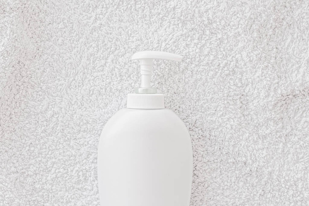 Blank label cosmetic container bottle as product mockup on white towel background - Foto, imagen