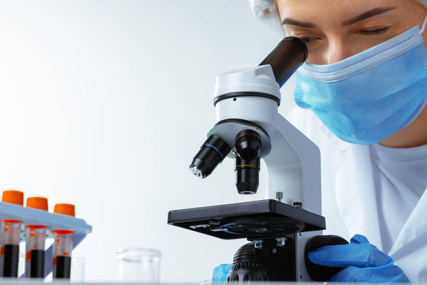 Woman scientist looking through a microscope in laboratory - Фото, зображення