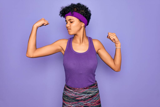 Beautiful african american afro woman wearing casual sportswear over purple background showing arms muscles smiling proud. Fitness concept. - Valokuva, kuva