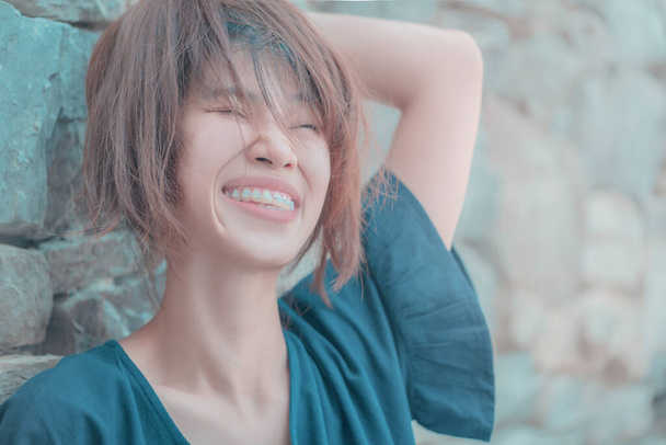 Aziatische vrouw met rommelig haar strak op zoek leuk en vrolijk met glimlach. Voor zorgeloze vrouw concept. - Foto, afbeelding