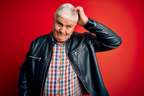 Senior handsome hoary man wearing casual shirt and jacket over isolated red background confuse and wonder about question. Uncertain with doubt, thinking with hand on head. Pensive concept. - Photo, Image