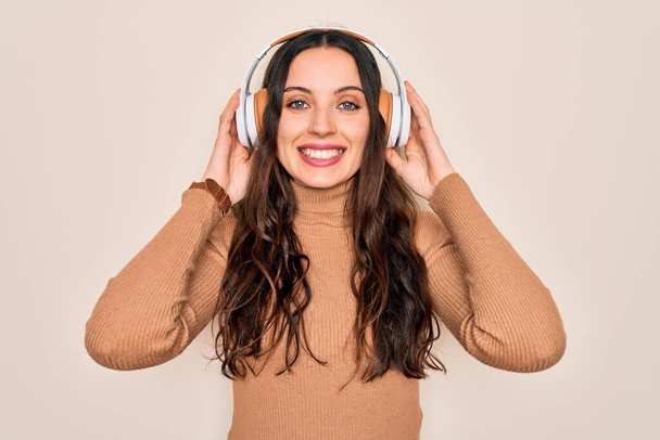Young beautiful woman with blue eyes listening to music and dancing using headphones with a happy face standing and smiling with a confident smile showing teeth - Fotó, kép