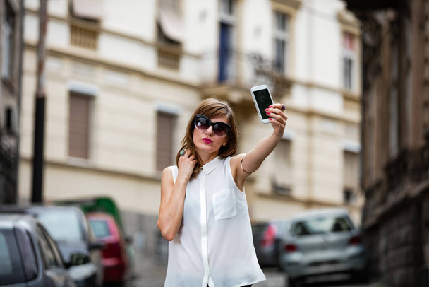 Vrouw met smartphone in het midden van een straat. - Foto, afbeelding