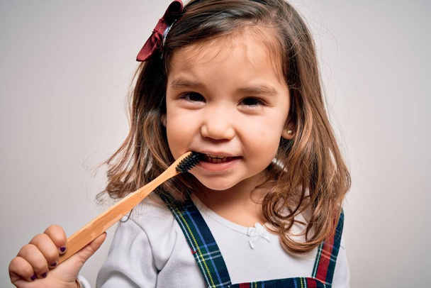 Young little infant girl brushing her teeth using tooth brush and oral paste, cleaning teeth and tongue as healthy health care morning routine. Learning dental education - 写真・画像