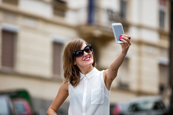Vrouw met smartphone in het midden van een straat. - Foto, afbeelding