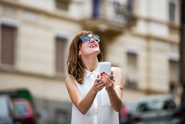 Mujer usando smartphone en medio de una calle
. - Foto, Imagen