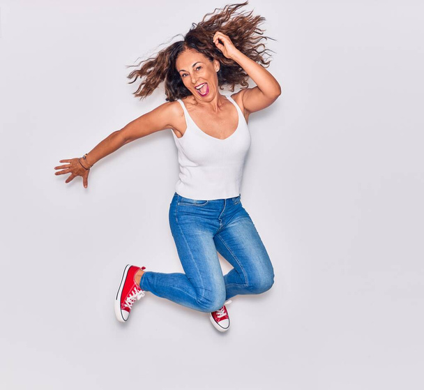 Middle age beautiful hispanic woman wearing casual clothes smiling happy. Jumping with smile on face over isolated white background - Foto, afbeelding