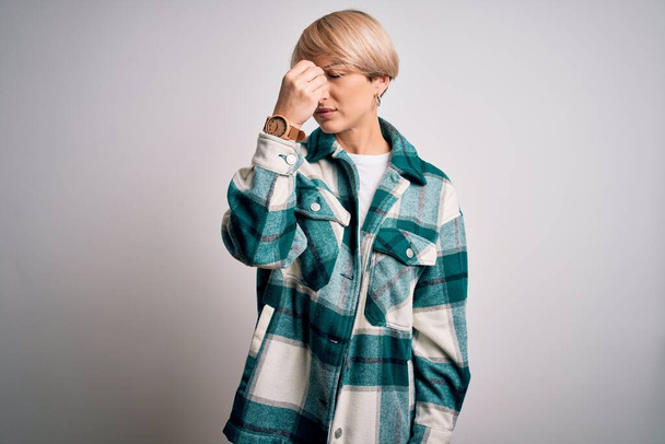 Young blonde woman with short hair wearing casual retro green shirt over isolated background tired rubbing nose and eyes feeling fatigue and headache. Stress and frustration concept. - Photo, image