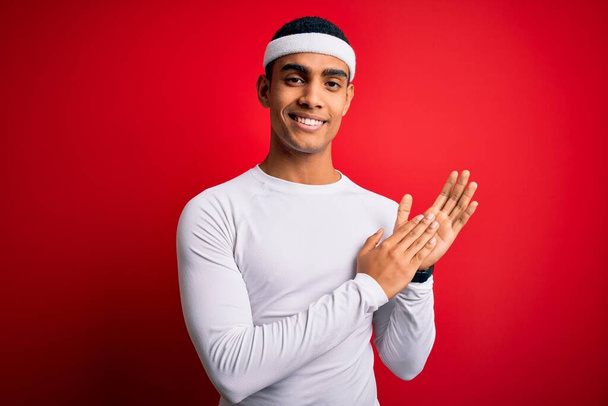 Young handsome african american sportsman wearing sportswear over red background clapping and applauding happy and joyful, smiling proud hands together - Fotoğraf, Görsel