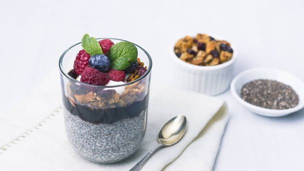 Chia pudding dessert with raspberry jam and granola, mint, blueberry, raspberry on the top. Healthy food. Copy space - Фото, изображение