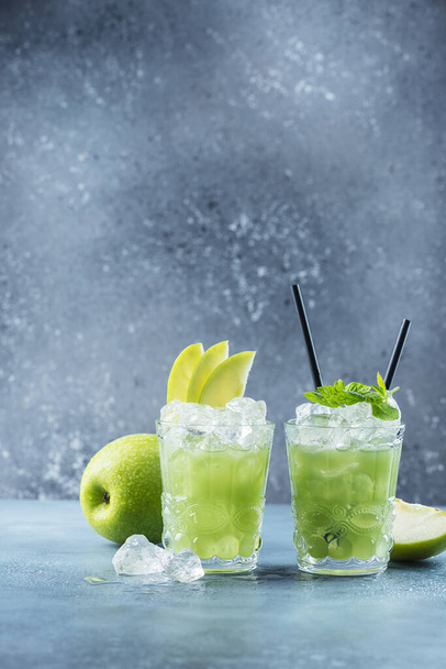 Green cocktail with ice and mint. Bar concept. Apple mojito with mint and ice on the blue background, selective focus image - Fotó, kép