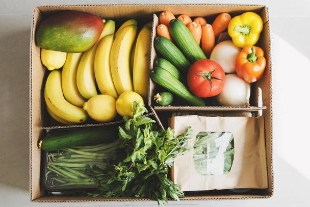 Kontaktloser Lebensmittellieferdienst. Frisches Obst, Kräuter und Gemüse in einer biologisch abbaubaren Papierbox. Lokale landwirtschaftliche Produkte - Foto, Bild