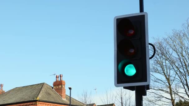 Brytyjskie światła drogowe zmienia się z zielonego na czerwone zbliżenie przeciwko jasnemu niebieskiemu niebu w jasny słoneczny dzień - Materiał filmowy, wideo