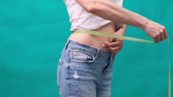 Κοντινό πλάνο μιας γυναίκας μετρά τη μέση της, την έννοια της διατροφής, την απώλεια βάρους και τη σωστή διατροφή. - Πλάνα, βίντεο