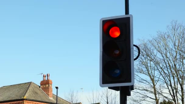 British Traffic Lights zmienia się z czerwonego na zielone zbliżenie przeciwko jasnemu niebieskiemu niebu w jasny słoneczny dzień - Materiał filmowy, wideo