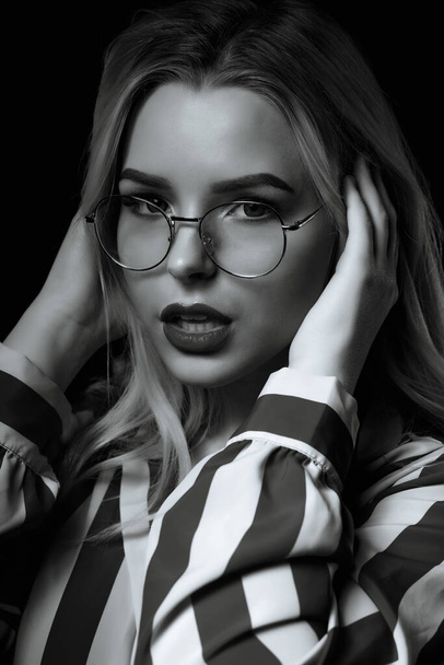 Dramatic portrait of seductive woman wears glasses posing in the shadow. Black and white color - Photo, Image