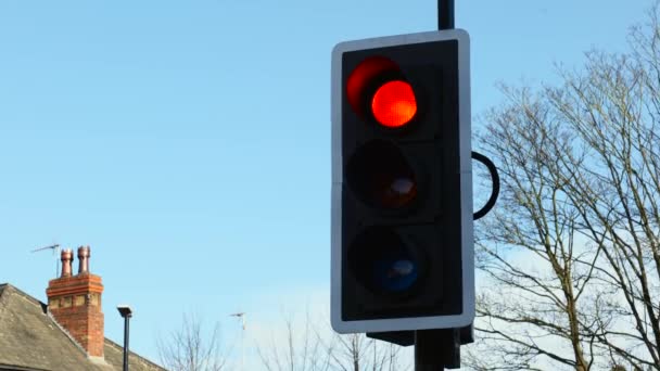 British Traffic Lights zmienia się z czerwonego na zielone zbliżenie przeciwko jasnemu niebieskiemu niebu w jasny słoneczny dzień - Materiał filmowy, wideo