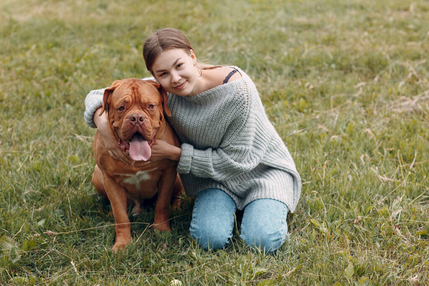 Dogue de Bordeaux or French Mastiff with young woman at outdoor park - Photo, Image