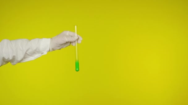 Ruka v latexové rukavici ochrana ukazuje skleněnou trubici se světle zelenou látkou - Záběry, video