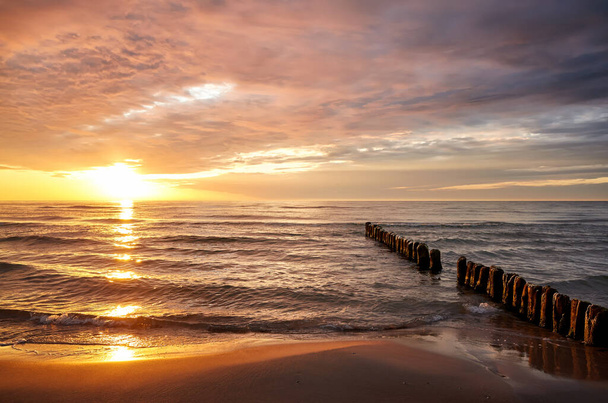 Strand egy régi hullámtörő gyönyörű naplemente a tenger felett. - Fotó, kép