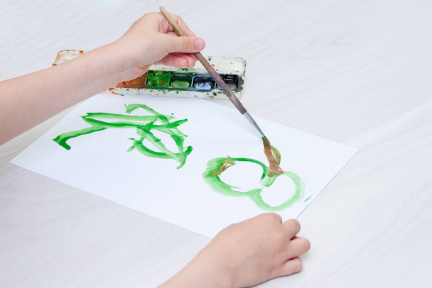 Левый ручной ребенок рисует картину на бумаге
. - Фото, изображение