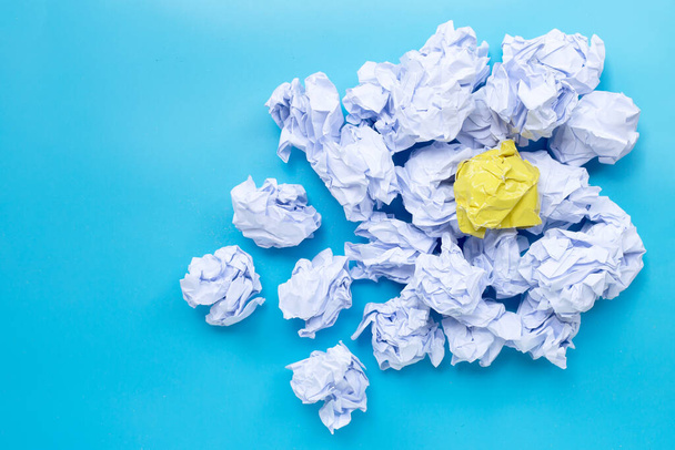 White and yellow crumpled paper balls on a blue background. Top view with copy space - 写真・画像