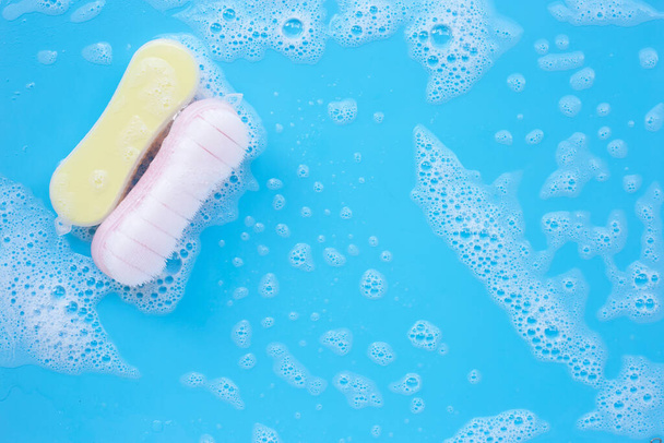 Cepillo para limpiar la ropa con espuma de detergente en polvo disolución de agua sobre fondo azul. Vista superior
 - Foto, Imagen
