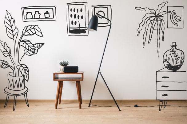 lámpara de pie, mesa de centro de madera y reloj con pantalla en blanco cerca de plantas dibujadas, pinturas y tocador
  - Foto, imagen