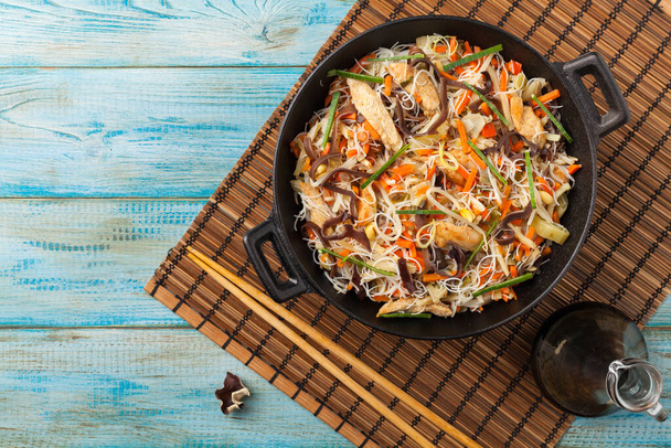 Rice noodles with chicken, mushrooms mun and vegetables, prepared in wook. Top view. - Фото, зображення