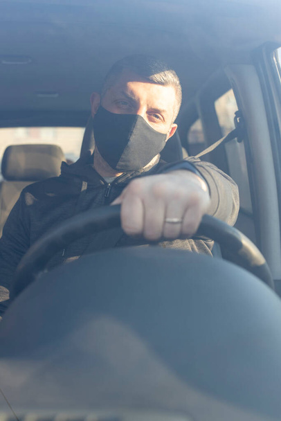 Людина в хірургічній масці в автомобілі, для вірусу корони або захисту Ковід-19.  - Фото, зображення