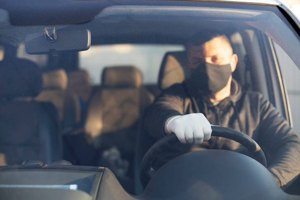 Muž s chirurgickou maskou v autě, na ochranu proti viru koróny nebo Covid-19.  - Fotografie, Obrázek