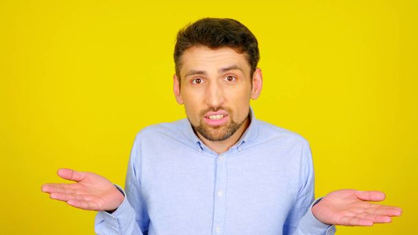 Man on a yellow background throws up his hands and does not know what to do - Photo, Image