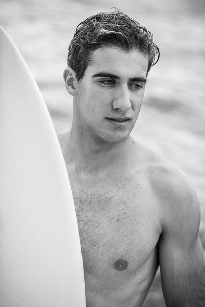 Black&white portrait of young surfer with white surfboard - Fotografie, Obrázek