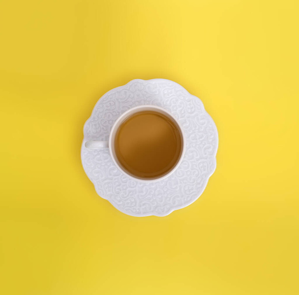 Фарфоровая чашка с чаем на желтом фоне. Элемент дизайна с траекторией обрезки
 - Фото, изображение