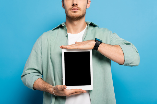 recortado vista de hombre joven mostrando tableta digital con pantalla en blanco en azul
 - Foto, imagen