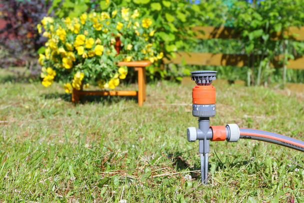 Оборудование для полива сада на фоне цветов и растений
. - Фото, изображение